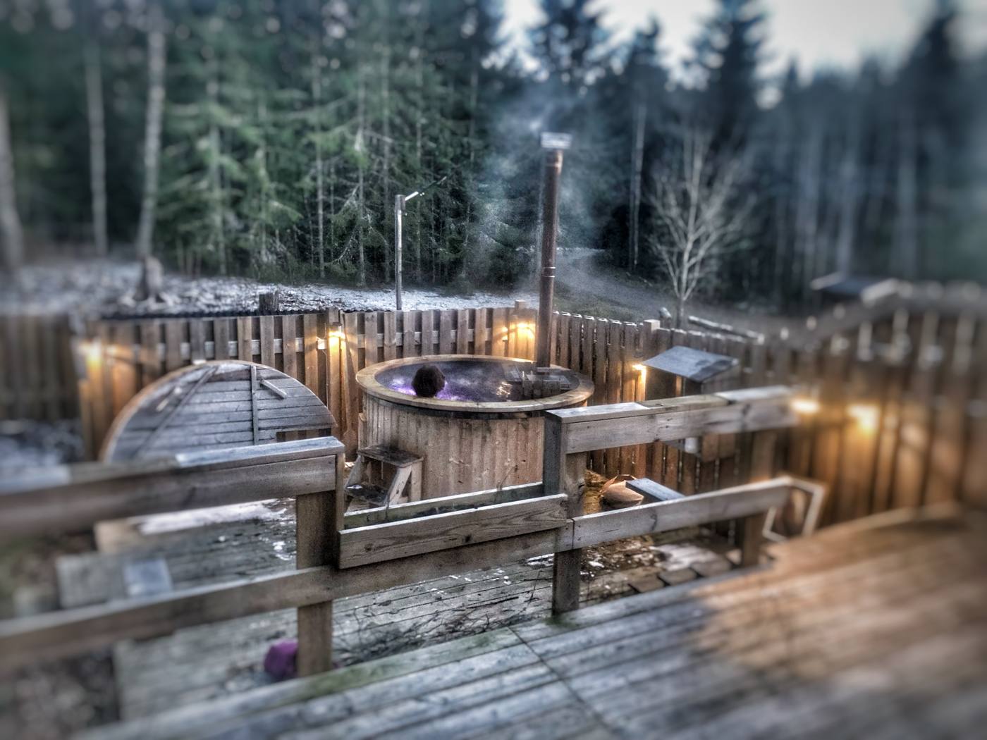 Holzbeheizte Badetonne an der Hinterterrasse, abends beleuchtet